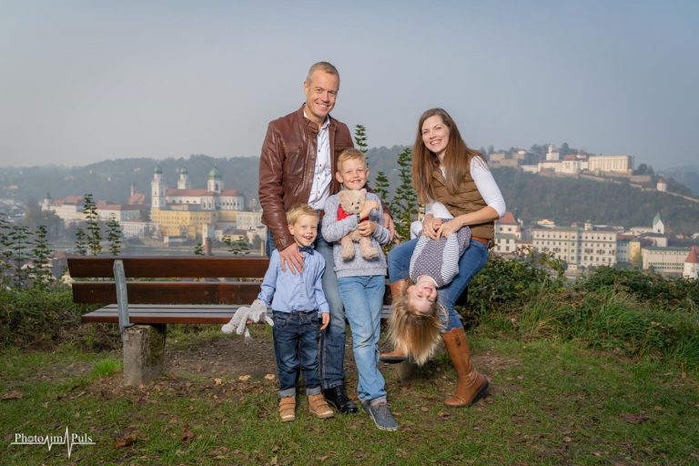 Familie mit drei Kindern auf einer Parkbank mit Blick über die Stadt