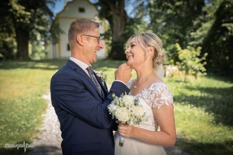 Melanie und Thomas lachen sich vor einer kleinen Kapelle an
