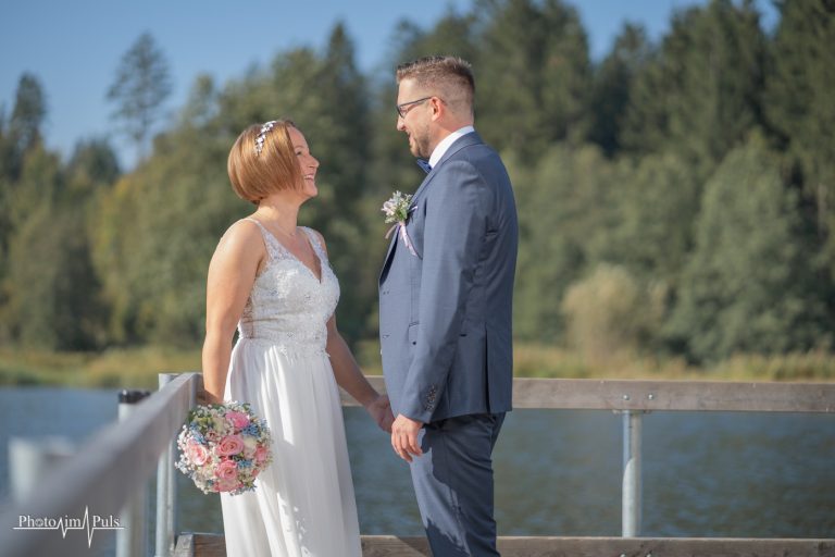 Brautpaar steht am Geländer mit Blick auf den See