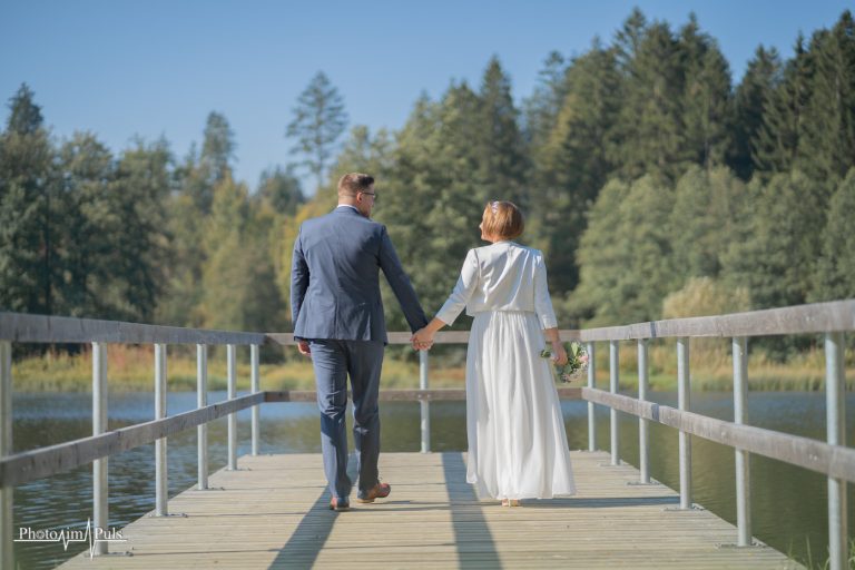 Brautpaar Hand in Hand auf dem Holzsteg am See