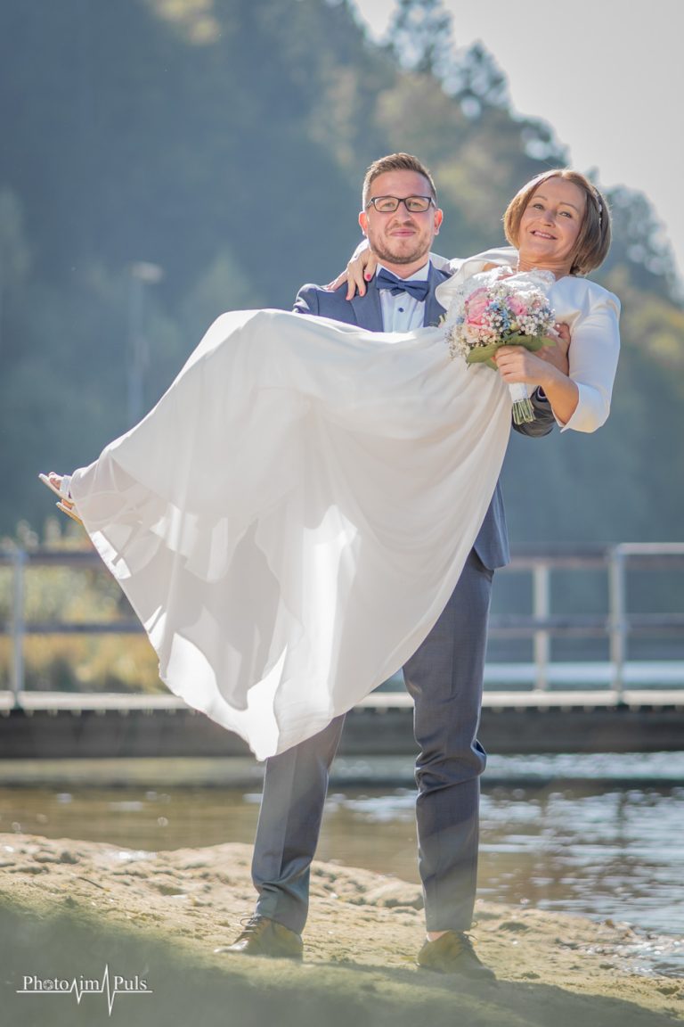 Marko trägt Charlotte auf Händen am Seeufer