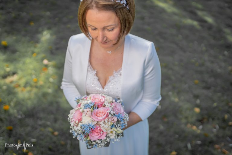 Charlotte blickt auf ihren Brautstrauß in Rosa und Blau