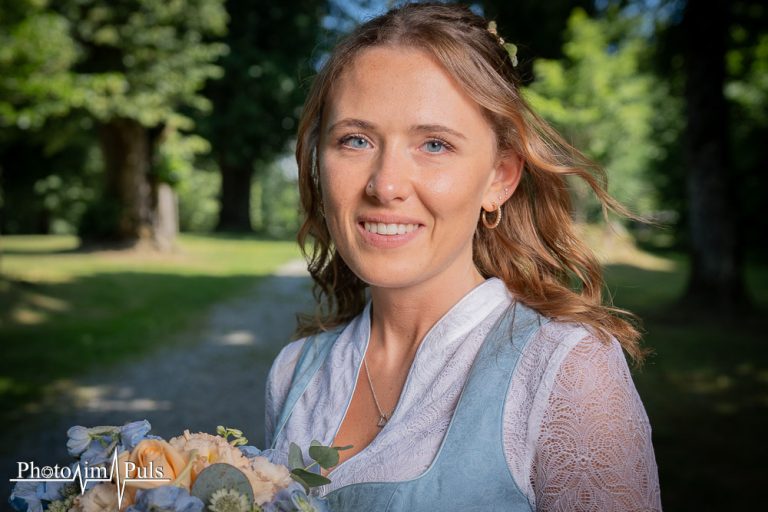 Portrait einer lächelnden Frau im Dirndl im Grünen