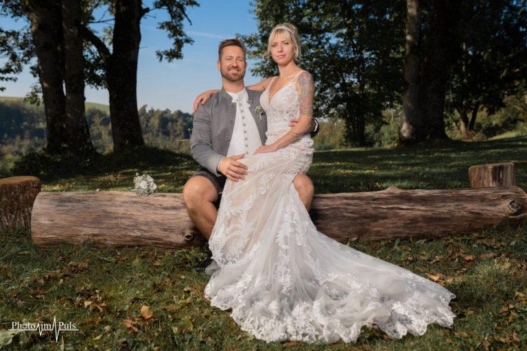 Jasmin und Johannes sitzen auf einem Baumstamm, Blick in die Kamera