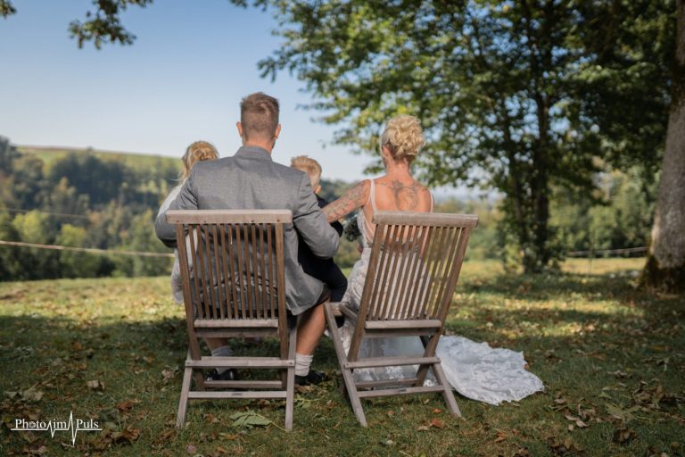 Jasmin und Johannes von hinten auf den Stühlen unter dem Baum
