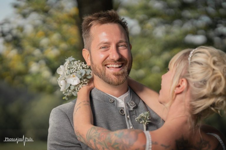 Johannes strahlt in die Kamera, Jasmin umarmt ihn